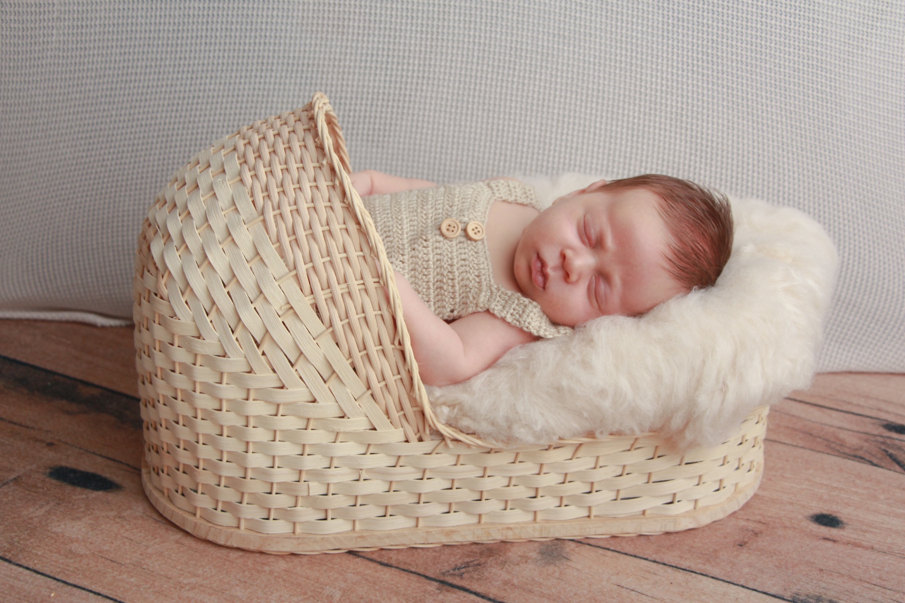 Sleeping newborn in a cream and white striped knit outfit